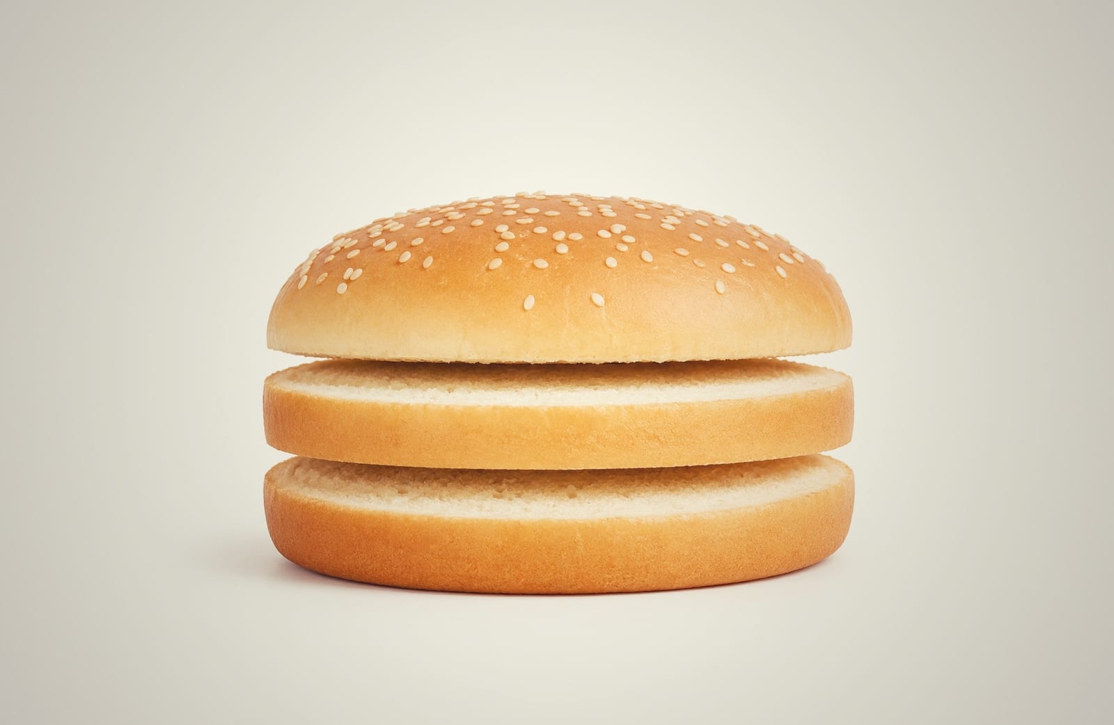 Three-piece burger bun separated into top, middle ring, and bottom sections after dual band blade cutting