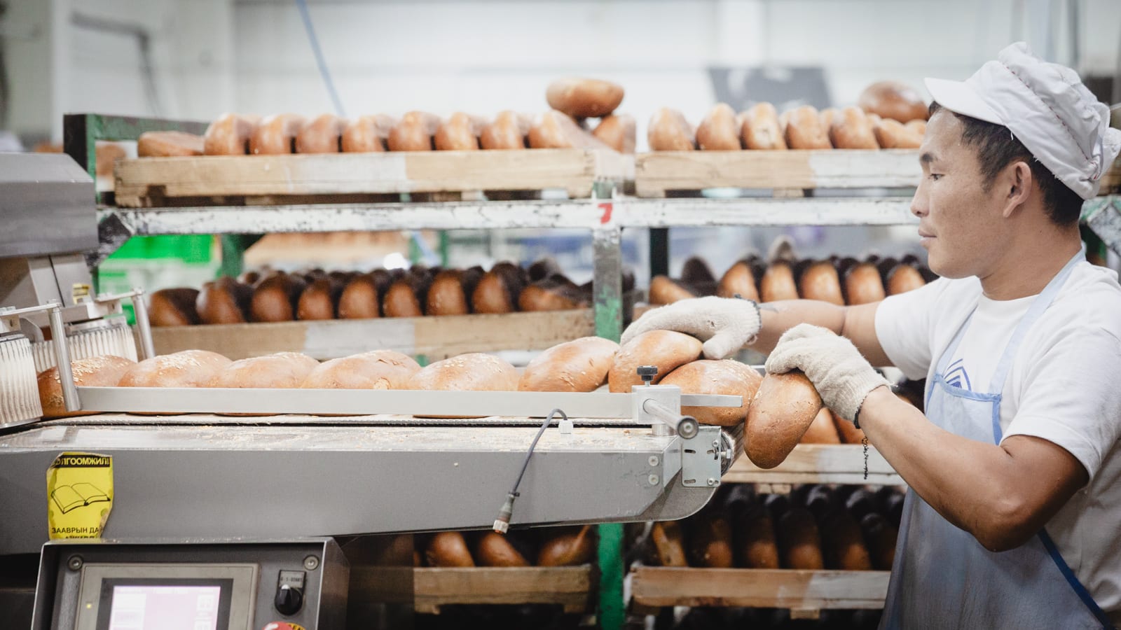 Bread slicer operator feeding bread into slicer